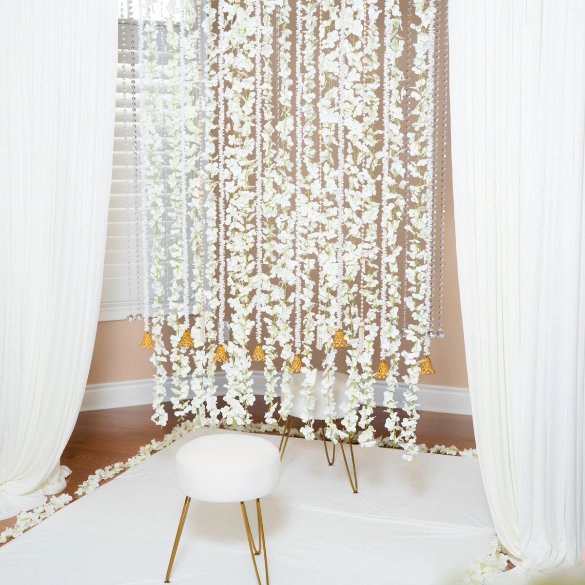 White floral strands and gold bells framing a petal-edged seating corner
